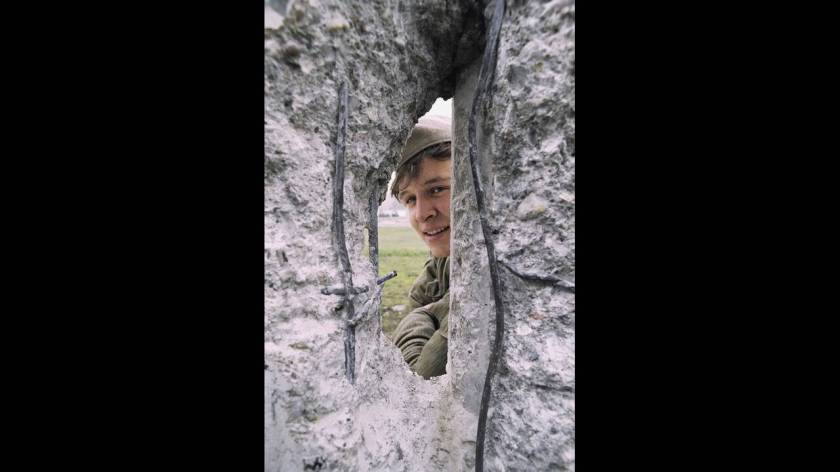 1989, Βερολίνο. Ένας Ανατολικογερμανός συνοριακός φρουρός κοιτάει μέσα από μια τρύπα του τείχους του Βερολίνου στην πλατεία Potsdamer. Το τείχος γκρεμίζεται από Δυτικογερμανούς που θέλουν να ενώσουν και πάλι την πόλη.